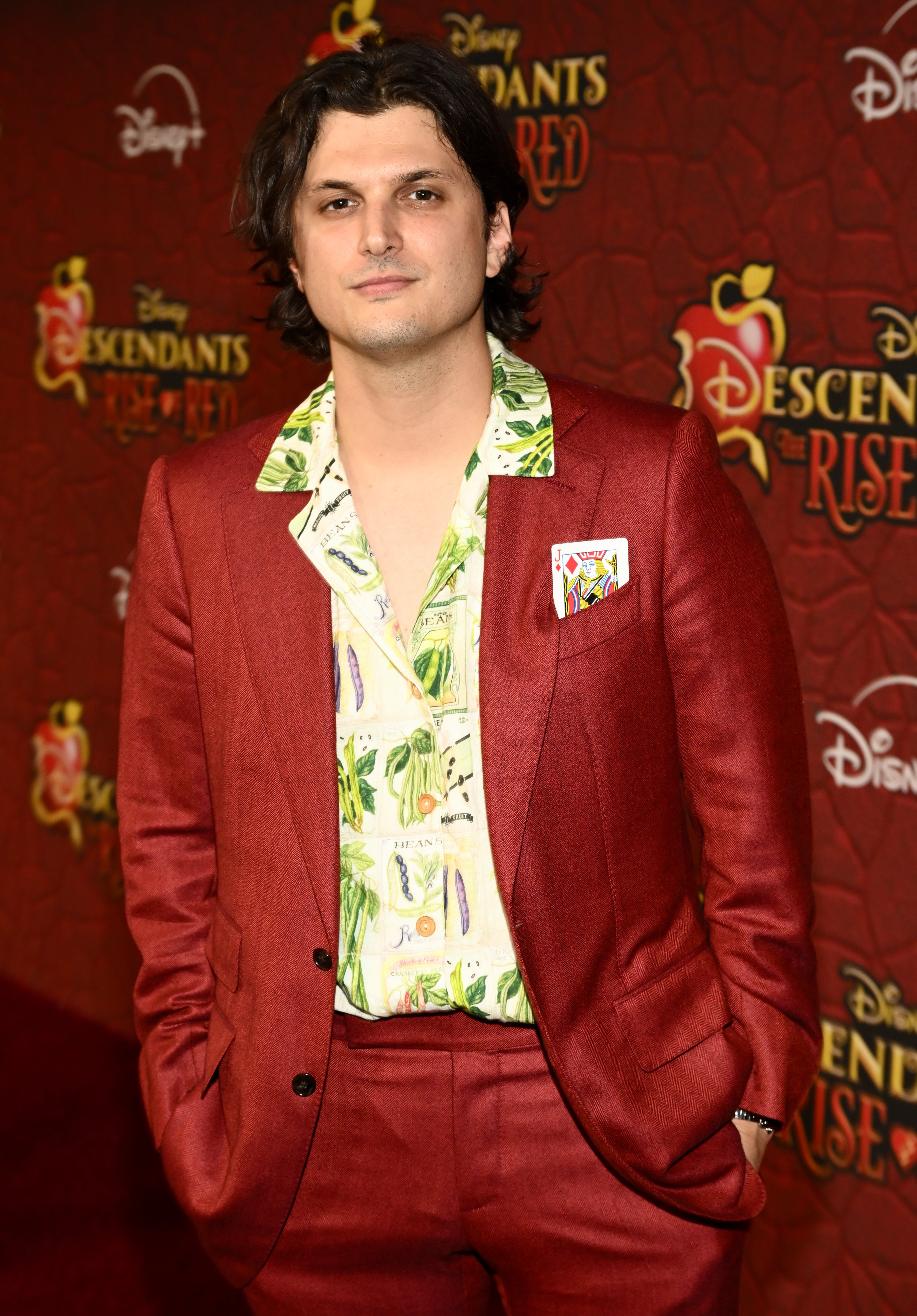 Alex Boniello on the red carpet for "Descendants: The Rise of Red" in a red suit with a Jacks playing card in his pocket