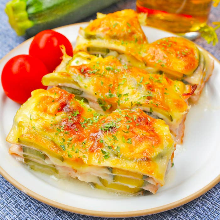 お皿に盛られた焼き野菜のラザニアとトマト2個。料理の上にはパセリが振りかけられている。