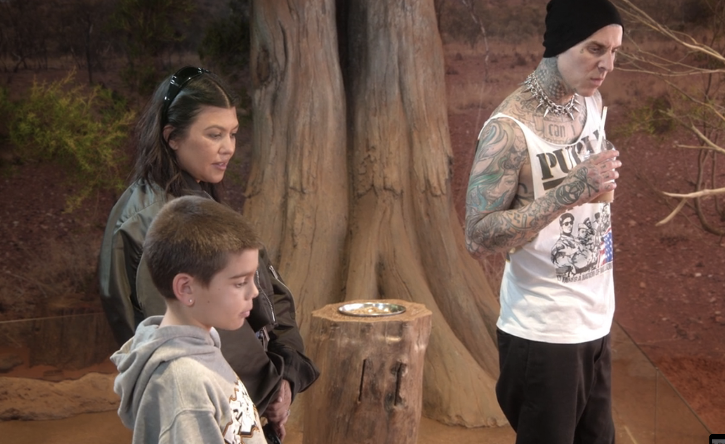 Kourtney Kardashian, Travis Barker, and Reign Disick observing an exhibit in a natural history setting