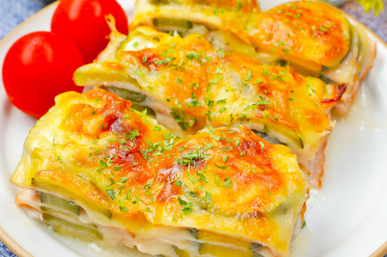 お皿に盛られた焼き野菜のラザニアとトマト2個。料理の上にはパセリが振りかけられている。