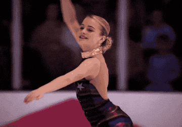 A skater performs a routine on an ice rink, wearing a stylish outfit with a shimmering collar