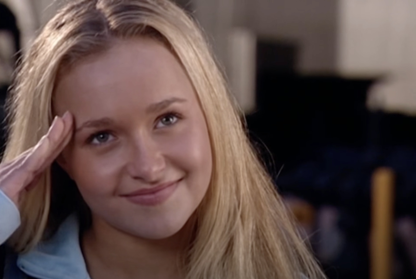 Hayden Panettiere smiles warmly and salutes with her right hand in an outdoor scene from a movie or TV show