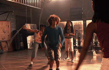 Group of young people, including a person with curly hair jumping rope, in a spacious gym setting
