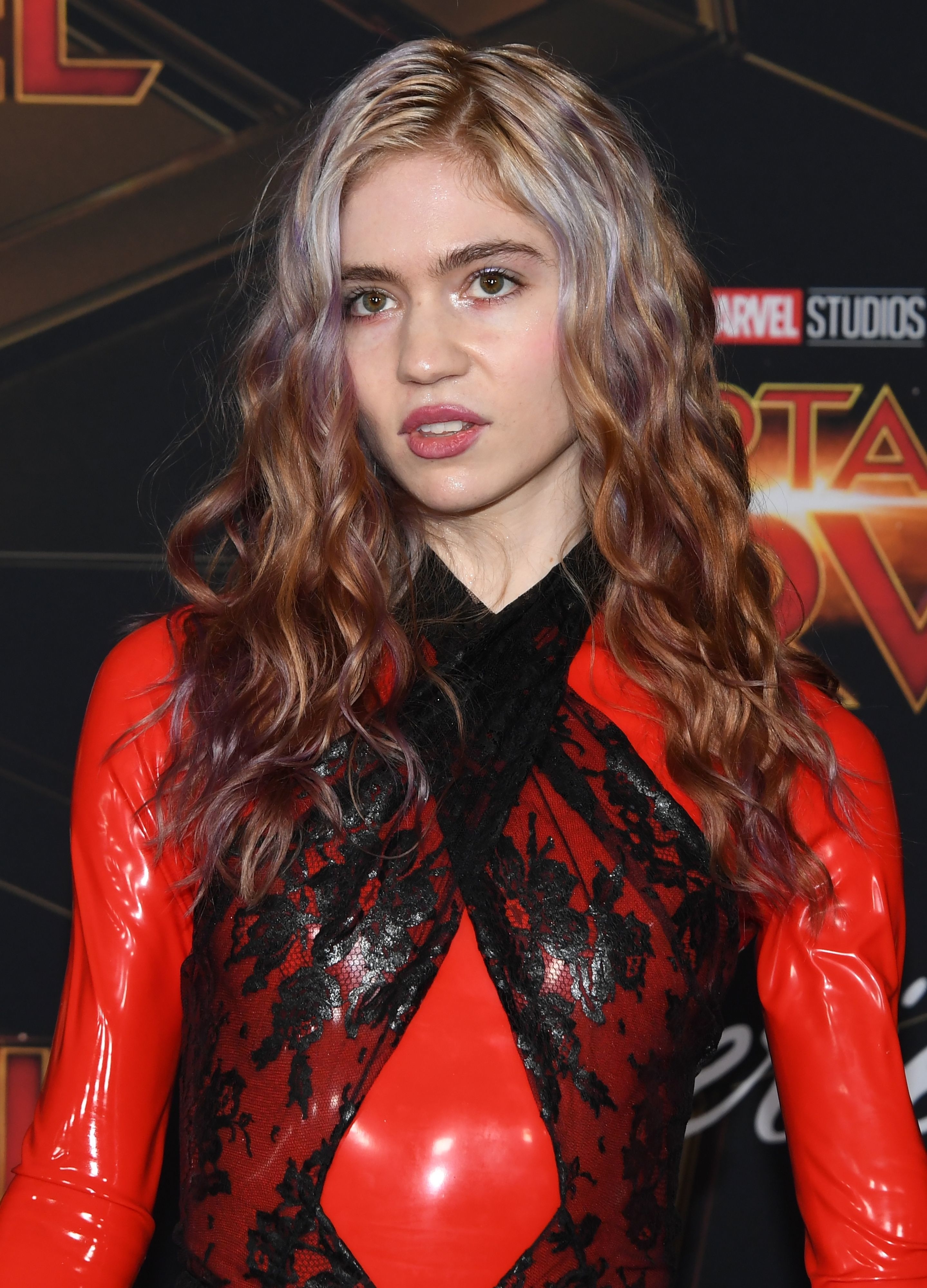 Grimes in a latex dress with lace details, posing at a Marvel Studios event