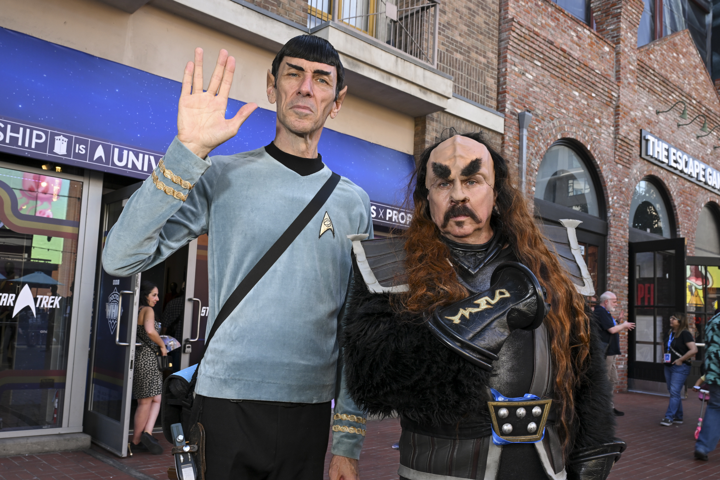 People dressed as Spock in a blue Starfleet uniform and a Klingon warrior from Star Trek pose together at an outdoor event