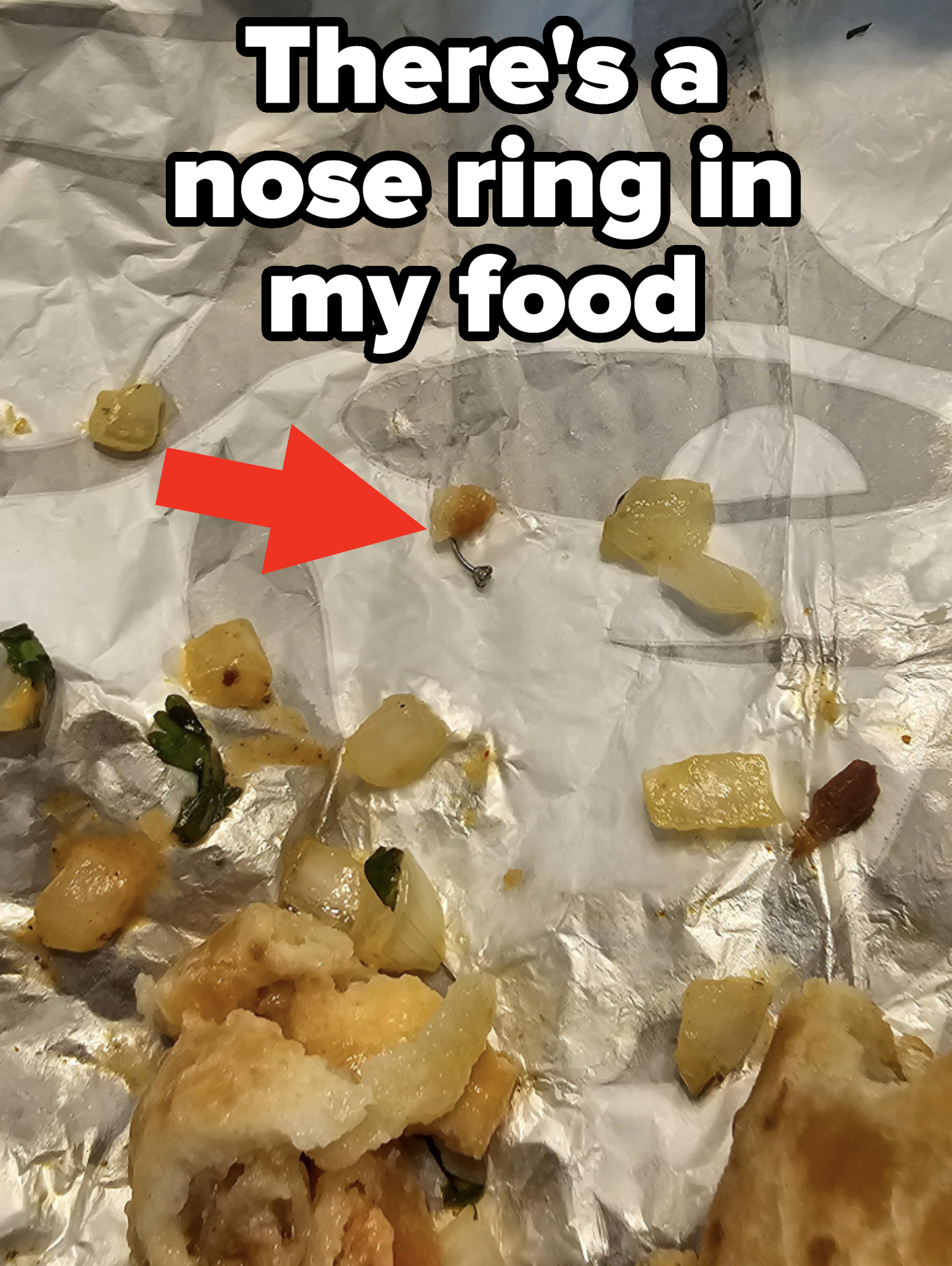 A partially eaten burrito with bits of onion, cilantro, and cheese on a crumpled fast-food wrapper