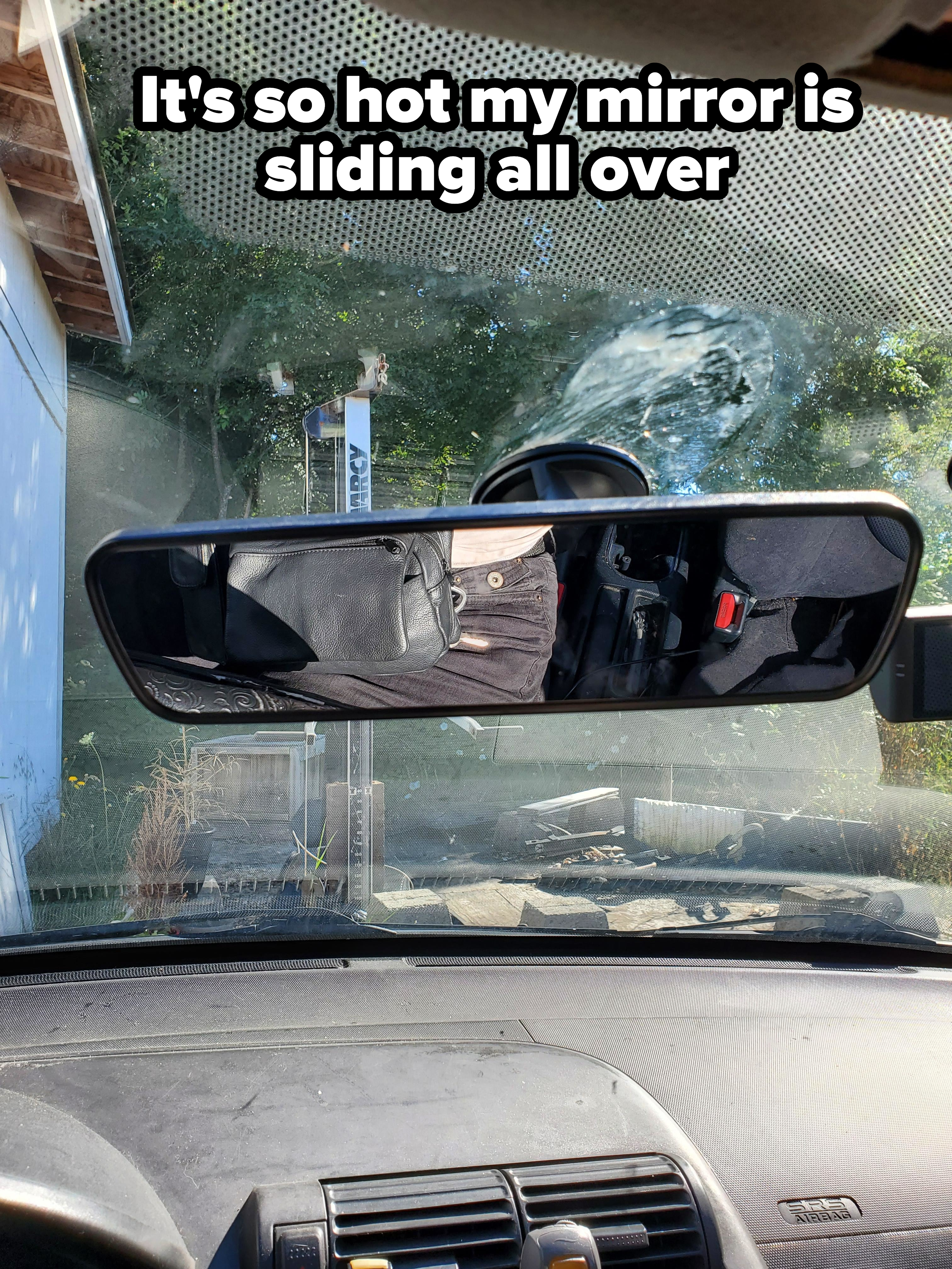 A rearview mirror reflects the image of button-up pants, placed in a way that makes them appear as if someone is in the back seat