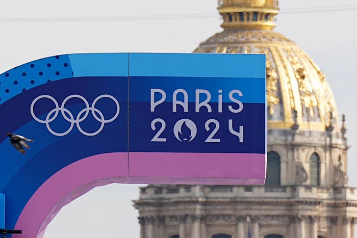 Olympic rings and "PARiS 2024" text on a sign with a domed building in the background