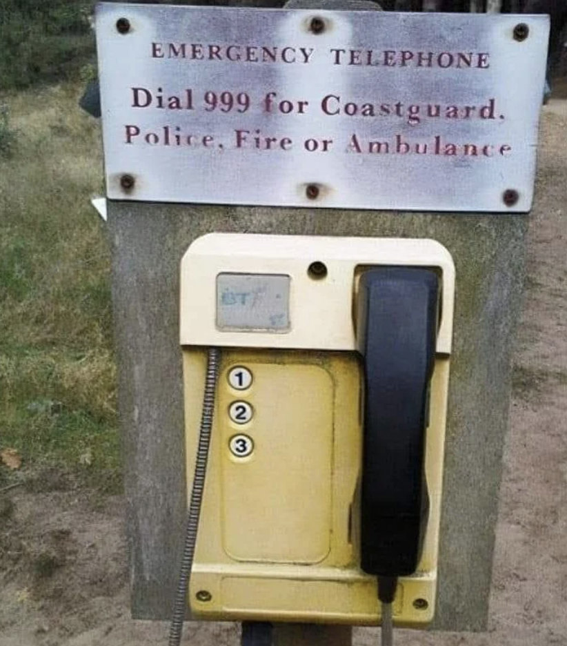 Emergency telephone with a sign instructing to dial 999 for Coastguard, Police, Fire, or Ambulance. The phone has labeled buttons 1, 2, and 3