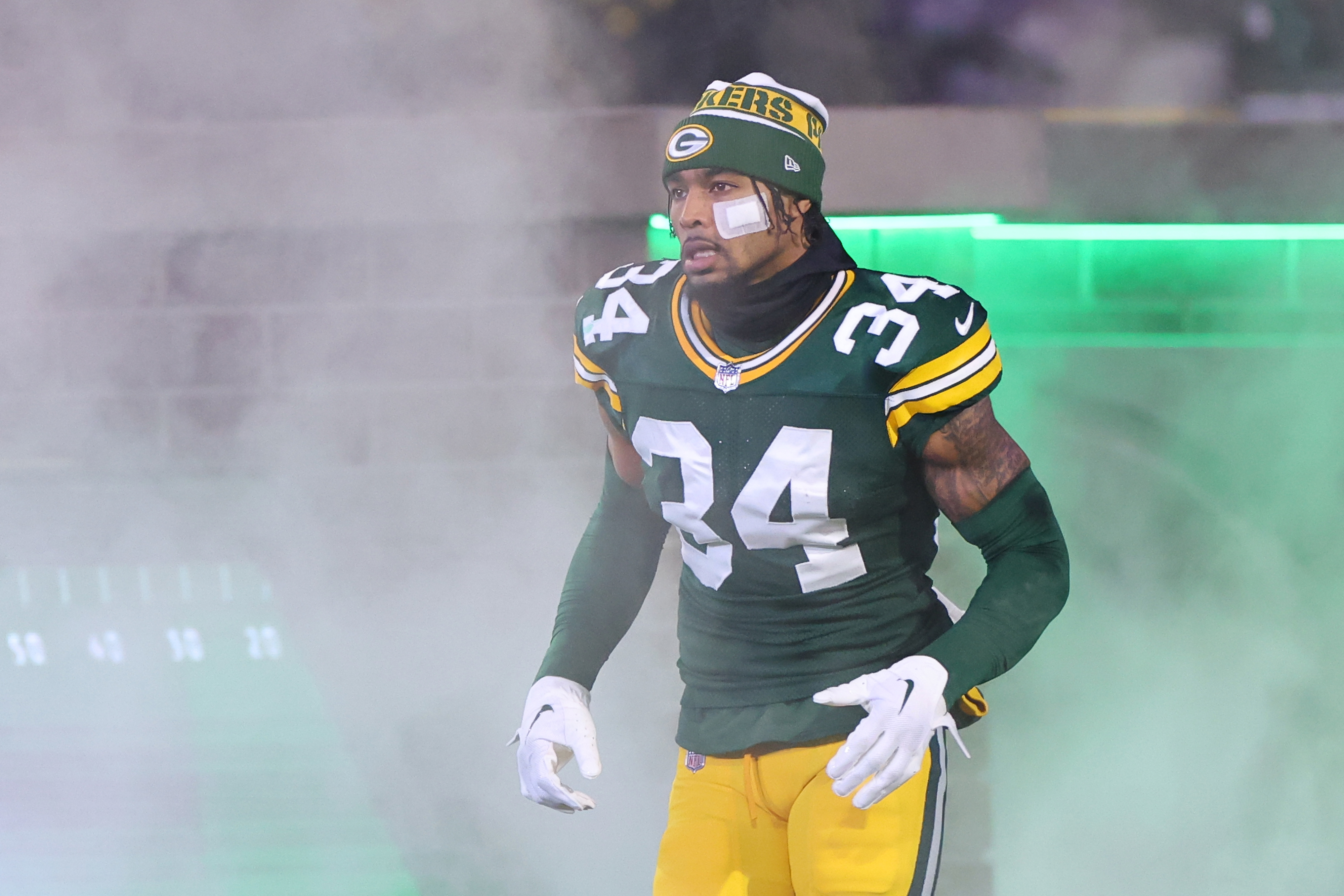 Packers player wearing number 34 jersey and helmet running onto the field through smoke before a game