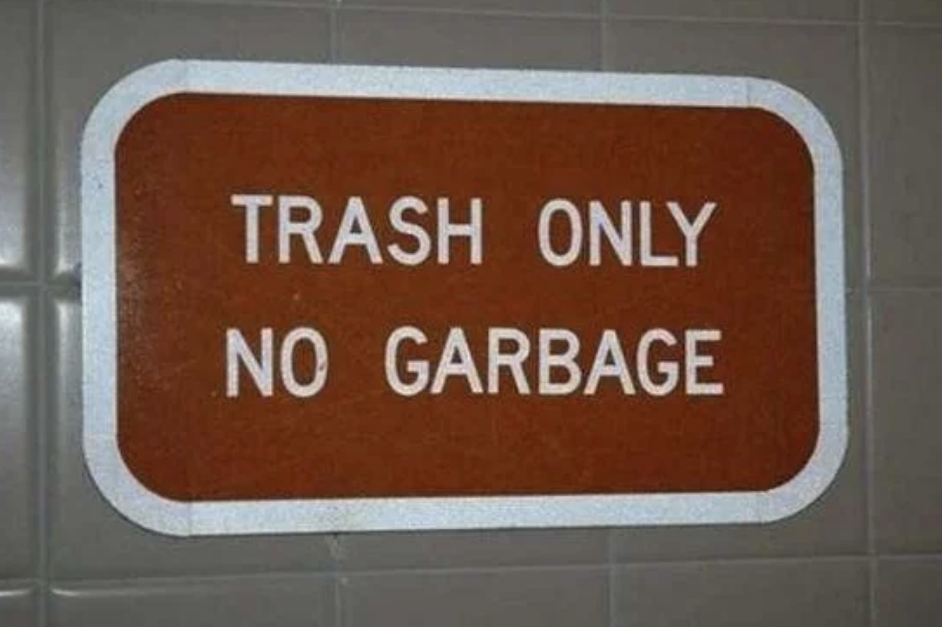 A sign on a tiled wall reads, "Trash Only No Garbage."