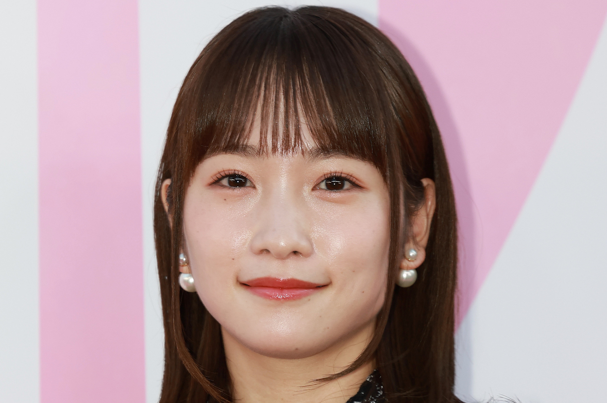 若い女性がフォトコールに登場。耳にパールのイヤリング、上質なツイードジャケットを着用。