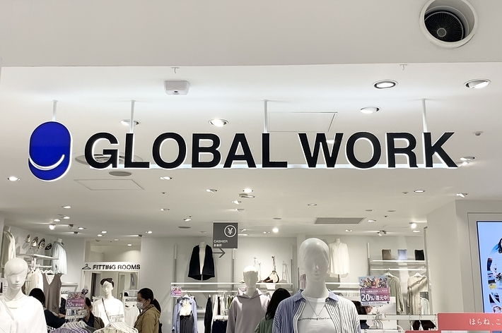 店内の「GLOBAL WORK」の看板が中央に掲示されています。背景には服が並んでおり、数名の買い物客がいます。