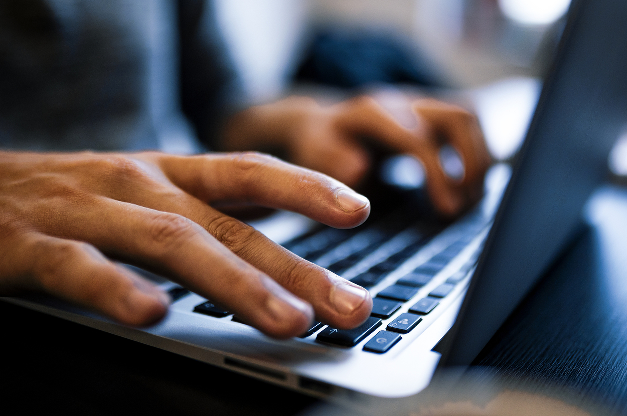 ノートパソコンのキーボードをタイピングする手元のクローズアップ写真。