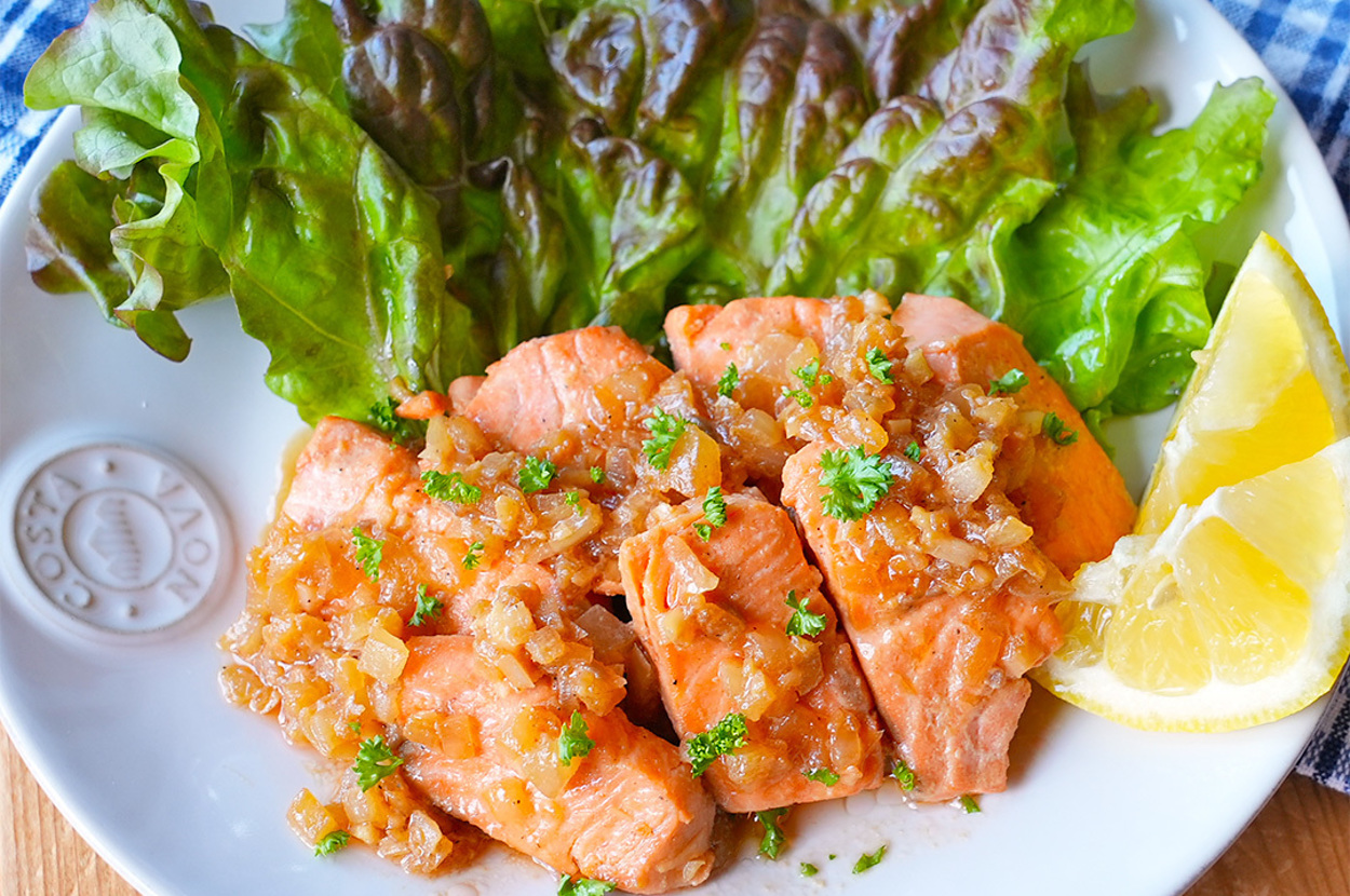 白い皿に盛られたサーモンのフィレ、レタス、レモンのくし切りが配された料理。
