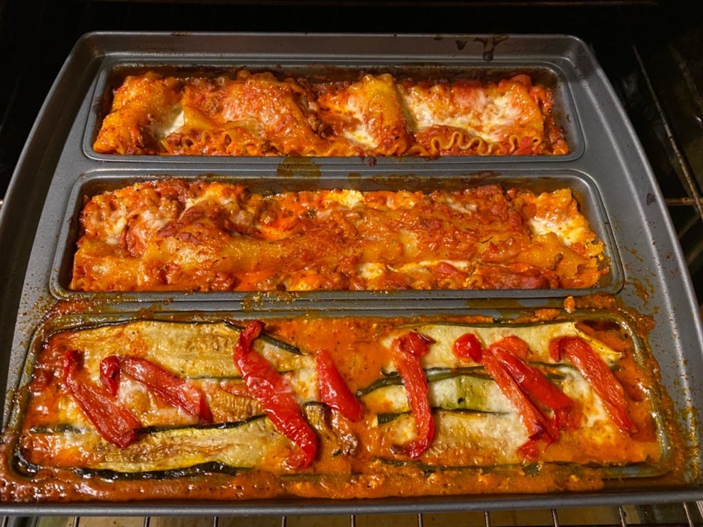 Three trays of baked lasagna, each with different toppings, in an oven. The lasagna is golden brown and looks appetizing