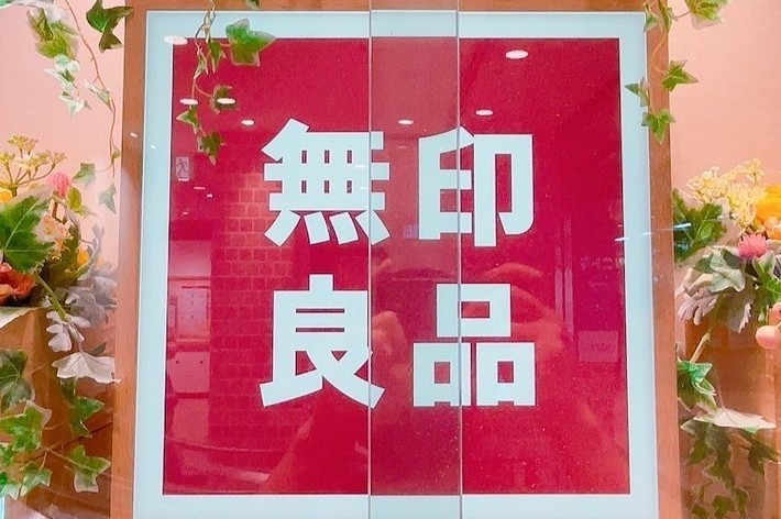 看板には大きく「無印良品」と書かれており、周囲には花の装飾が施されています。