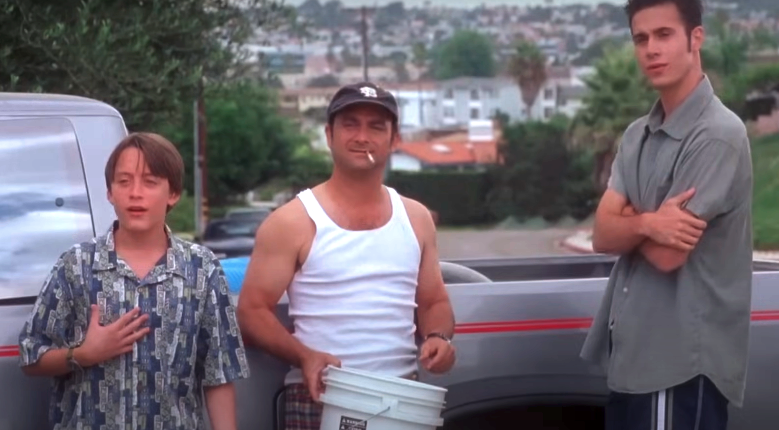 Kieran Culkin, Kevin Pollak, and Freddie Prinze Jr. stand by a truck in a suburban setting; Culkin looks surprised, Pollak holds a bucket, and Prinze crosses his arms