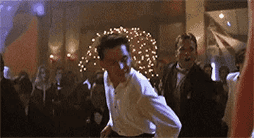 Jack Dawson, played by Leonardo DiCaprio, is dancing enthusiastically with a crowd at a lively party scene in the movie "Titanic."
