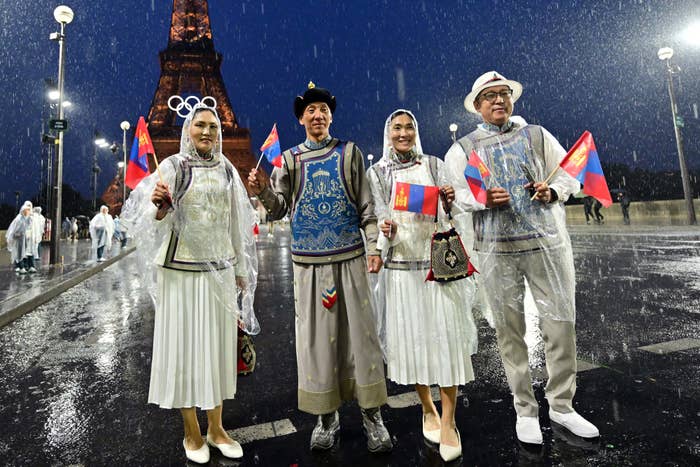 Group in traditional attire holding flags in the rain near the Eiffel Tower during an event