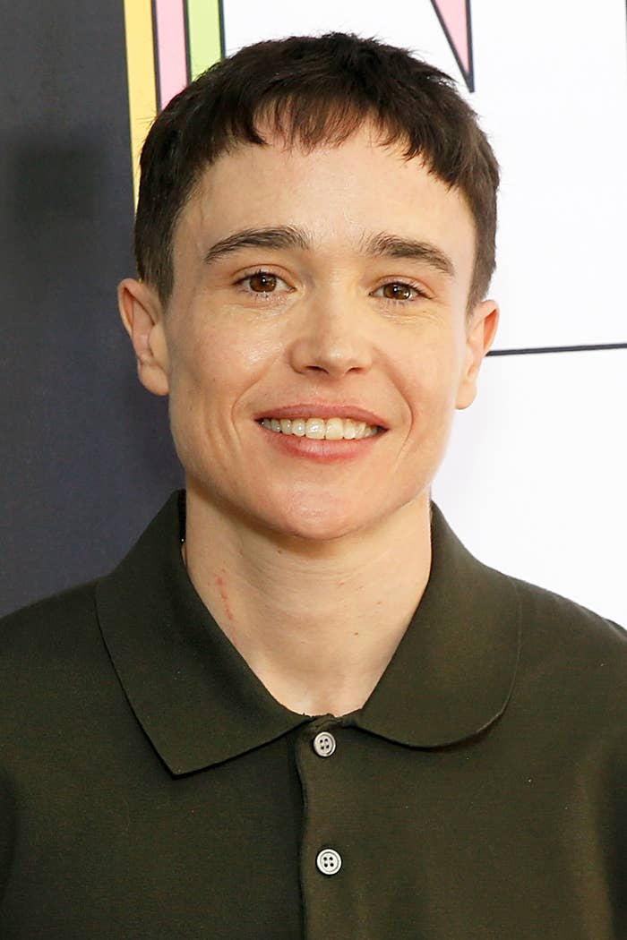 Elliot Page smiling at an event, wearing a casual buttoned polo shirt