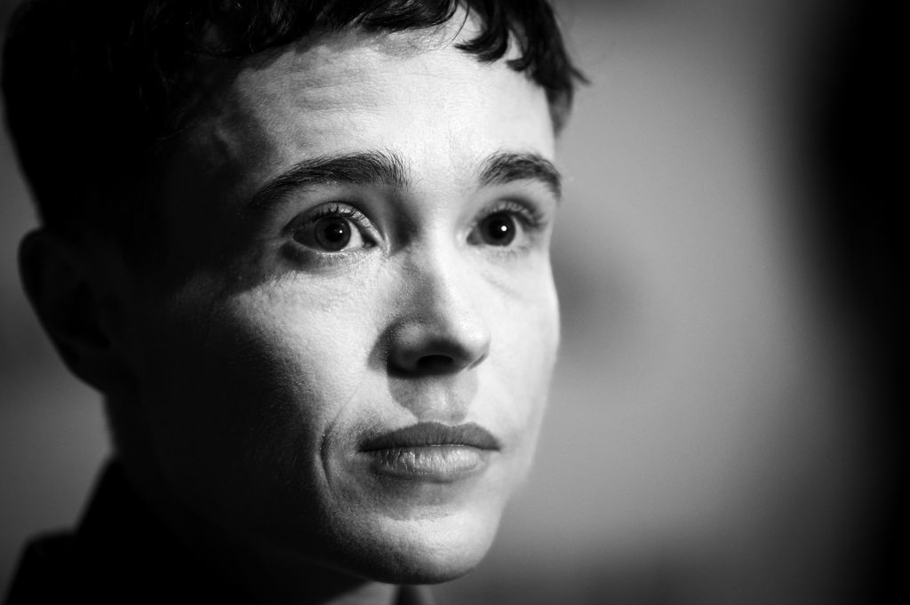 Elliot Page in a close-up black and white photograph, gazing upward with a calm expression