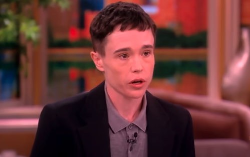 Elliot Page, wearing a blazer and collared shirt, speaks during an interview on a daytime talk show