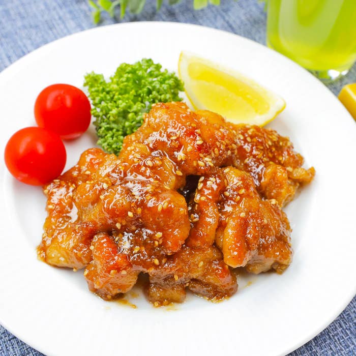 白い皿に盛られた照り焼きチキン、レモンのくし切り、ブロッコリー、ミニトマト。