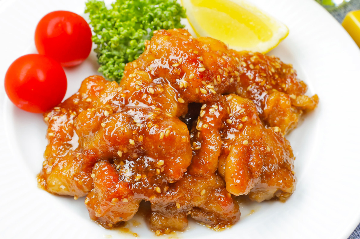 白い皿に盛られた照り焼きチキン、レモンのくし切り、ブロッコリー、ミニトマト。