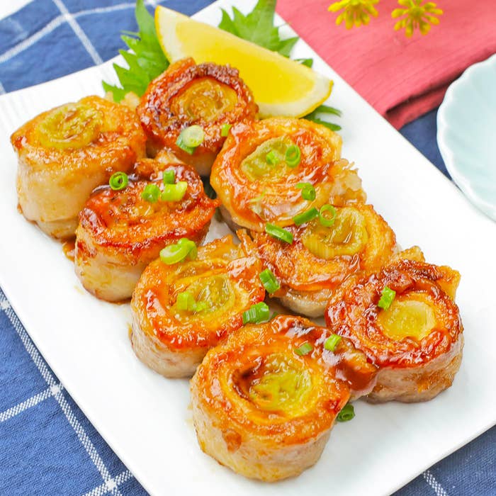 白い皿に盛られた料理。上には刻んだネギがトッピングされ、レモンスライスが添えられている。