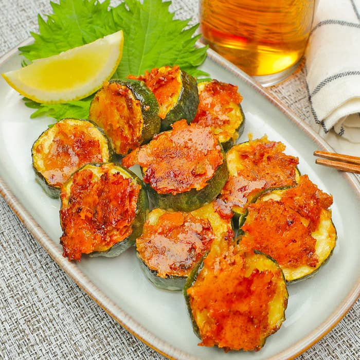 プレートにのったチーズ焼きズッキーニの料理。左上にレモンのくし形が添えられている。