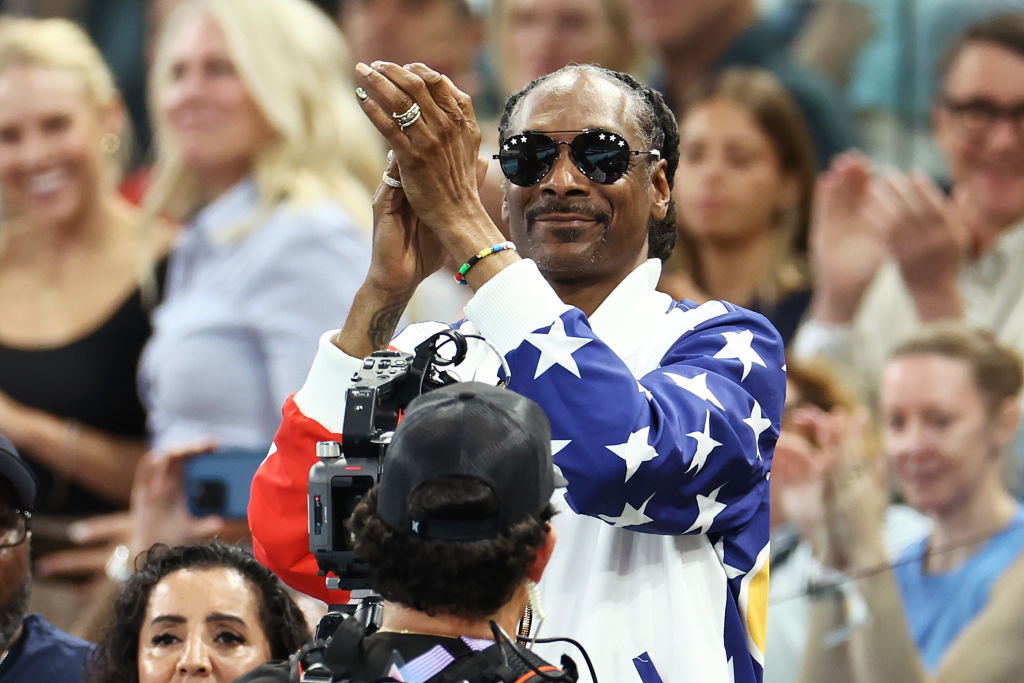 Snoop Dogg clapping in the audience, wearing a star-patterned jacket and sunglasses