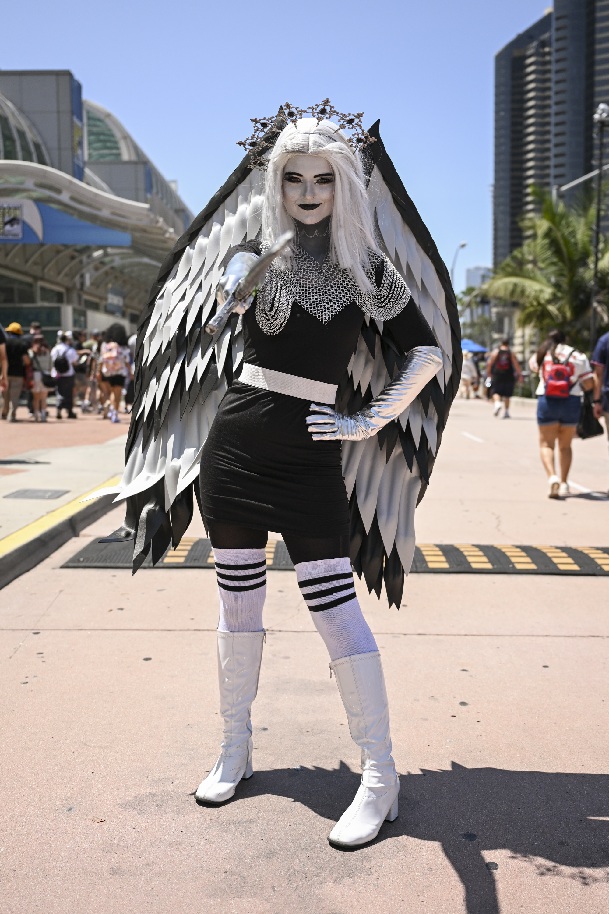 Person in a black and white costume with large feathered wings and metallic accessories poses outside a convention center
