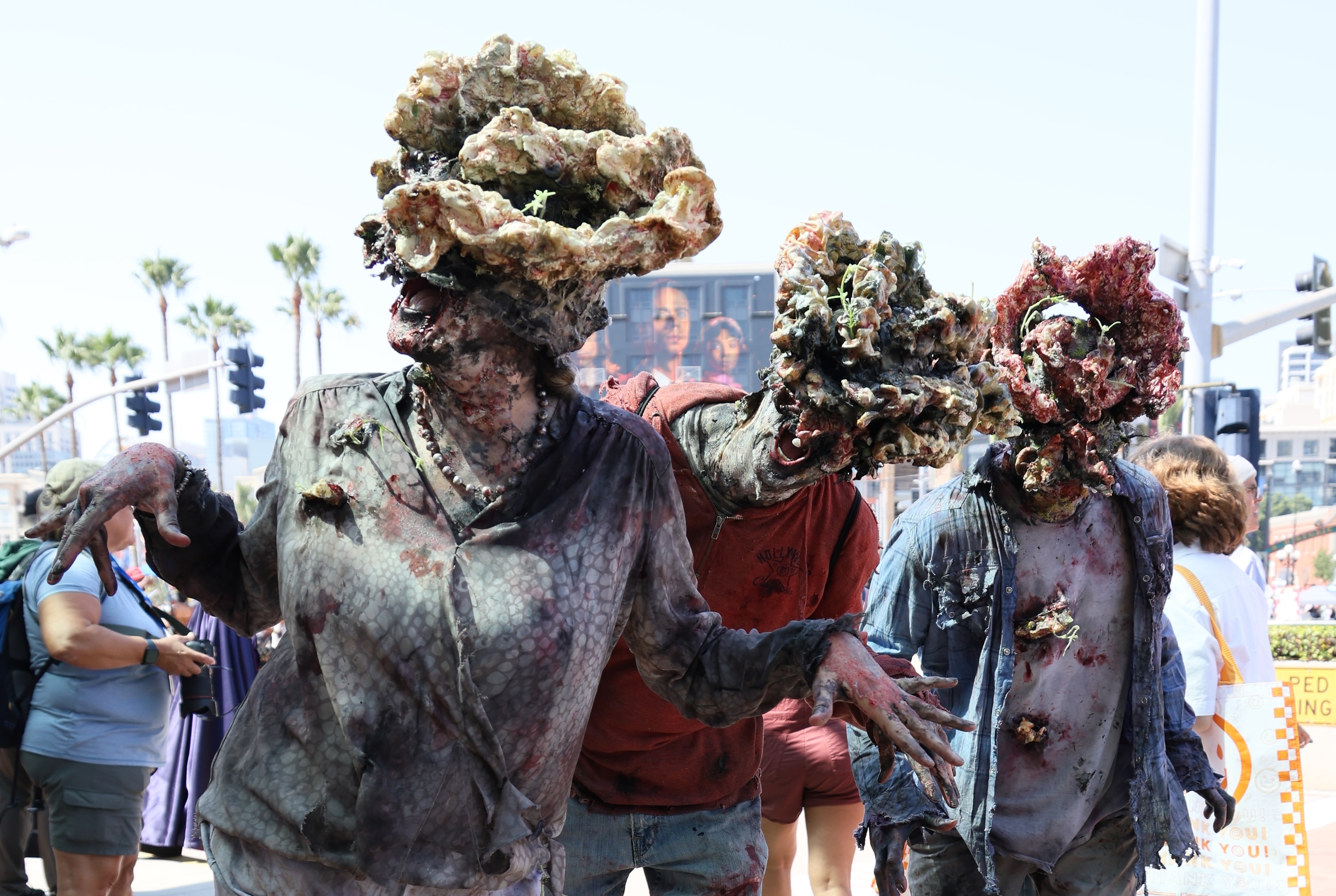 Actors portraying the Clickers from "The Last of Us" TV series exhibit detailed, monstrous fungi-infested designs at a public event
