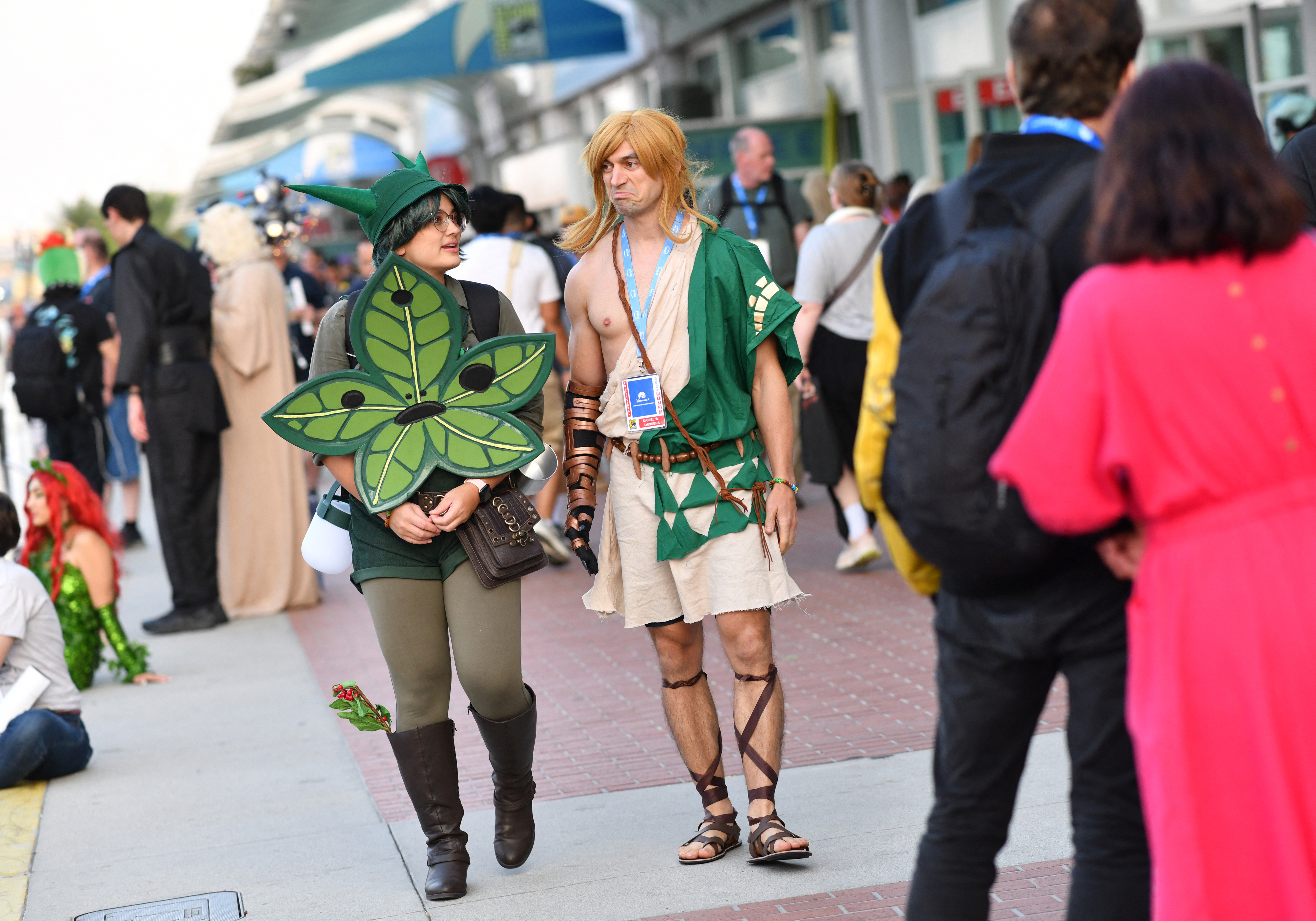 Two people in cosplay at a convention: one dressed as Link from The Legend of Zelda series, and the other as a Kokiri from The Legend of Zelda series