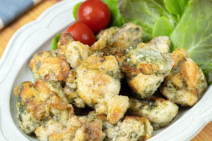 白い皿に盛られた揚げ鳥肉とレタス、プチトマトの料理。