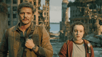 Pedro Pascal and Bella Ramsey in character from &quot;The Last of Us,&quot; walking through a post-apocalyptic city landscape