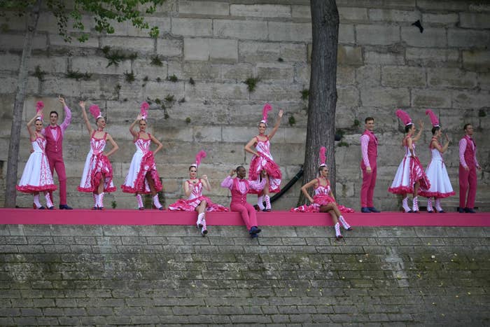 Performers in elaborate outfits pose on a stone stage for a choreographed sports event