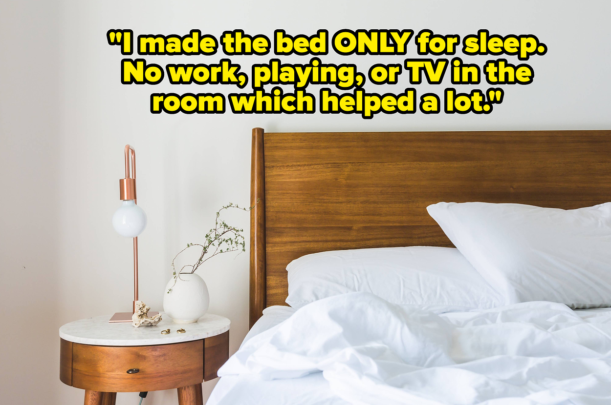 A bed with white bedding, a wooden bed frame, and nightstand with a lamp and plant vase Text: "I made the bed ONLY for sleep. No work, playing, or TV in the room which helped a lot. My body knows as soon as it's horizontal that it's time for sleep."