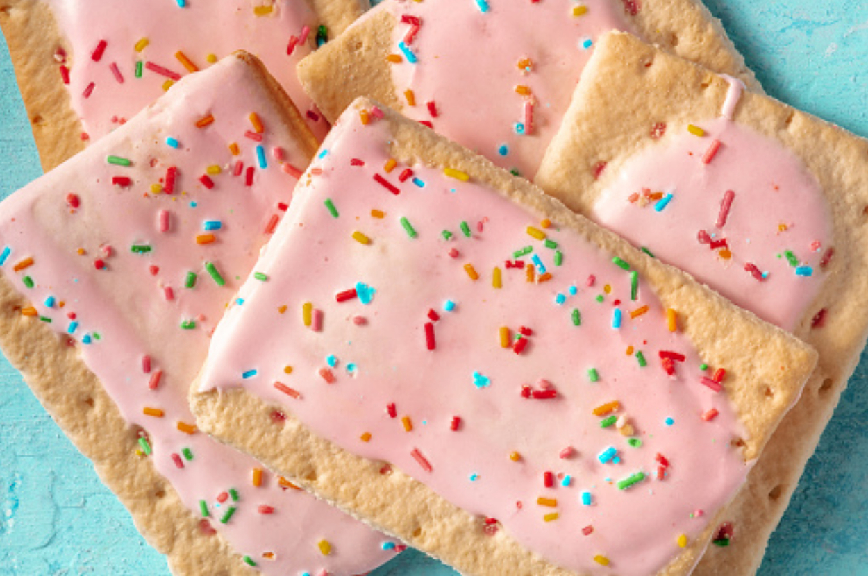 Several pink frosted toaster pastries with colorful sprinkles on a light blue surface