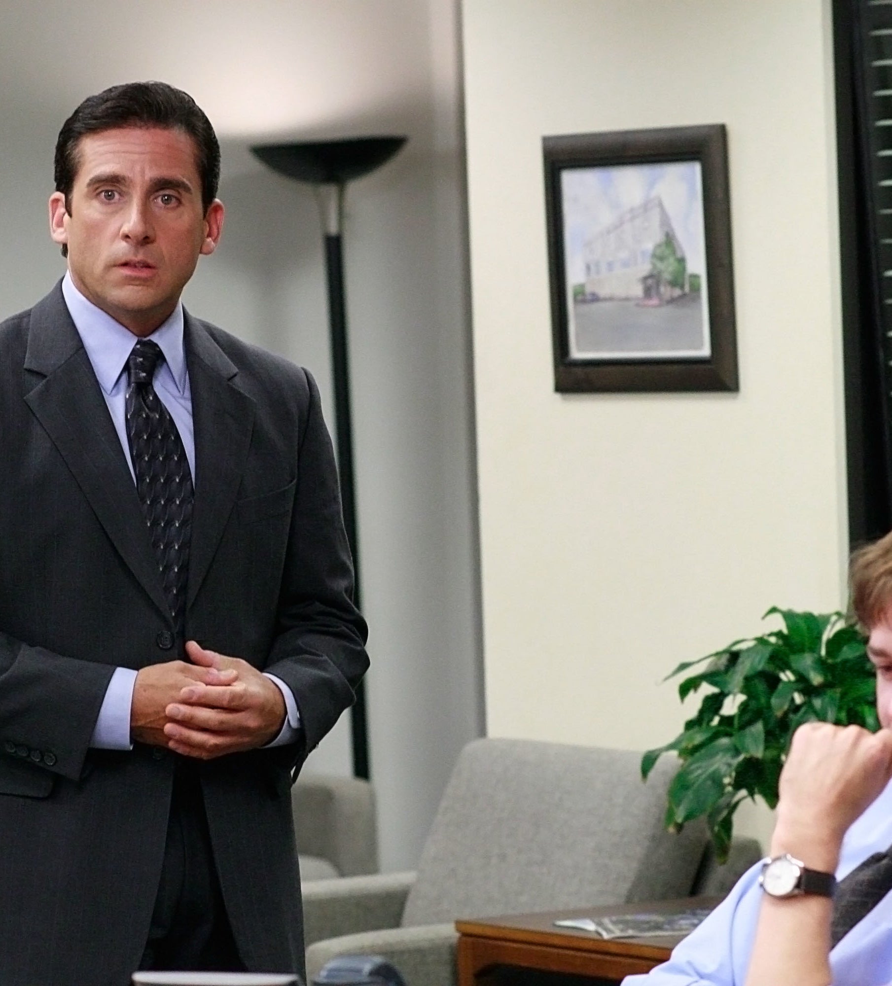 Steve Carell in a suit stands in an office