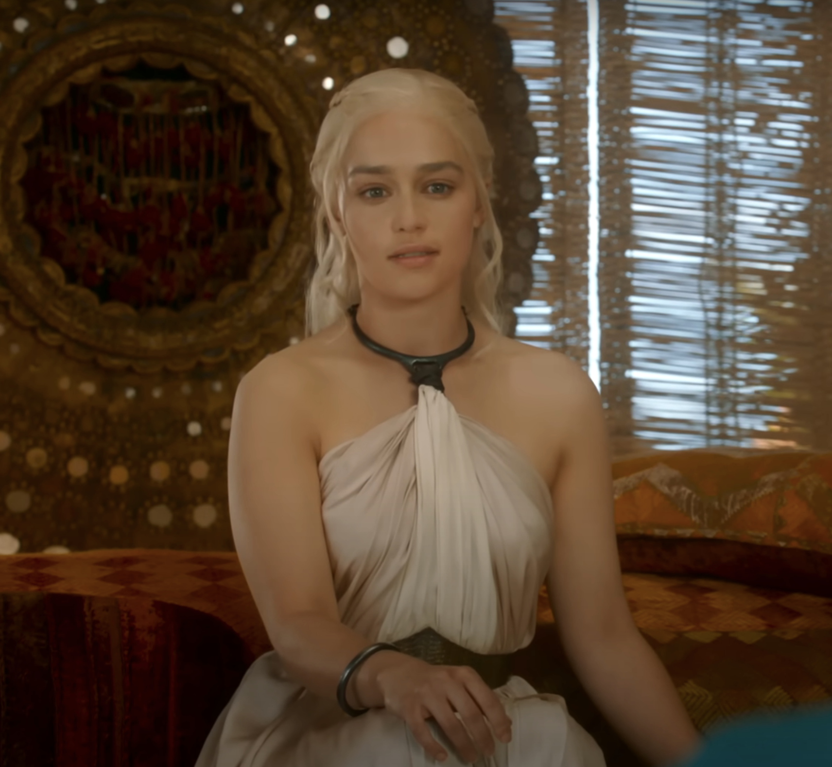 Emilia Clarke, as Daenerys Targaryen, sits in a room wearing a Grecian-style dress in a scene from the TV series &quot;Game of Thrones.&quot;