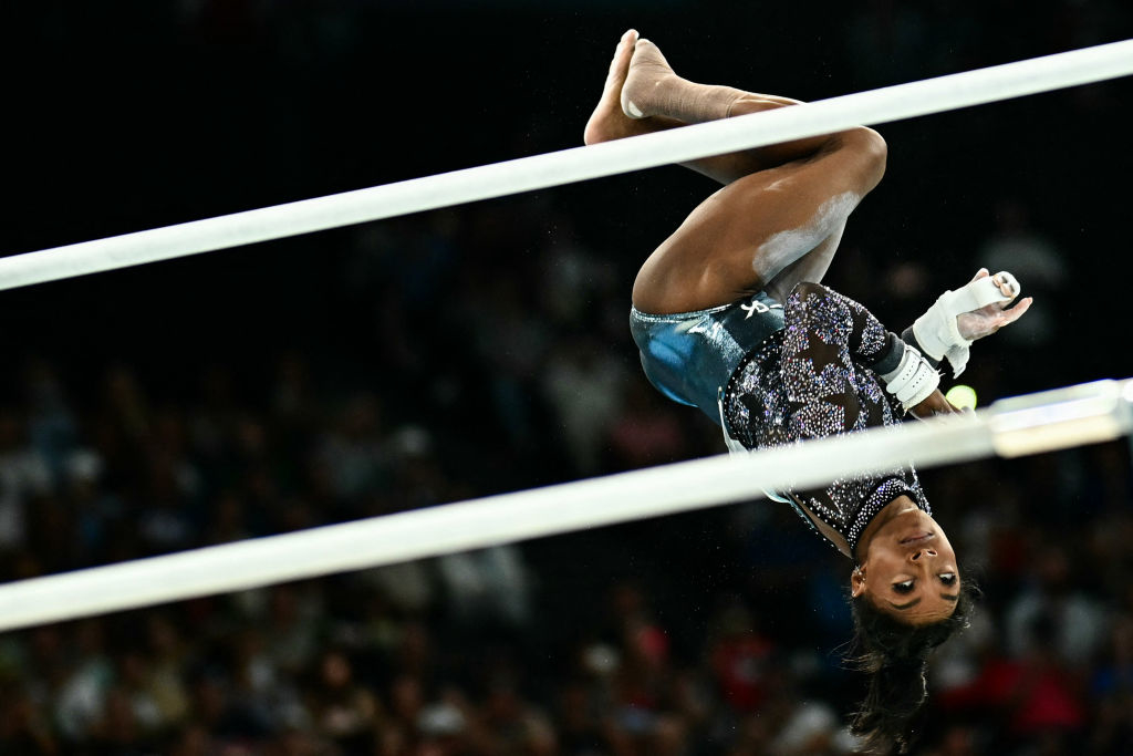 Simone Biles performs an impressive flip on the uneven bars during a gymnastics competition
