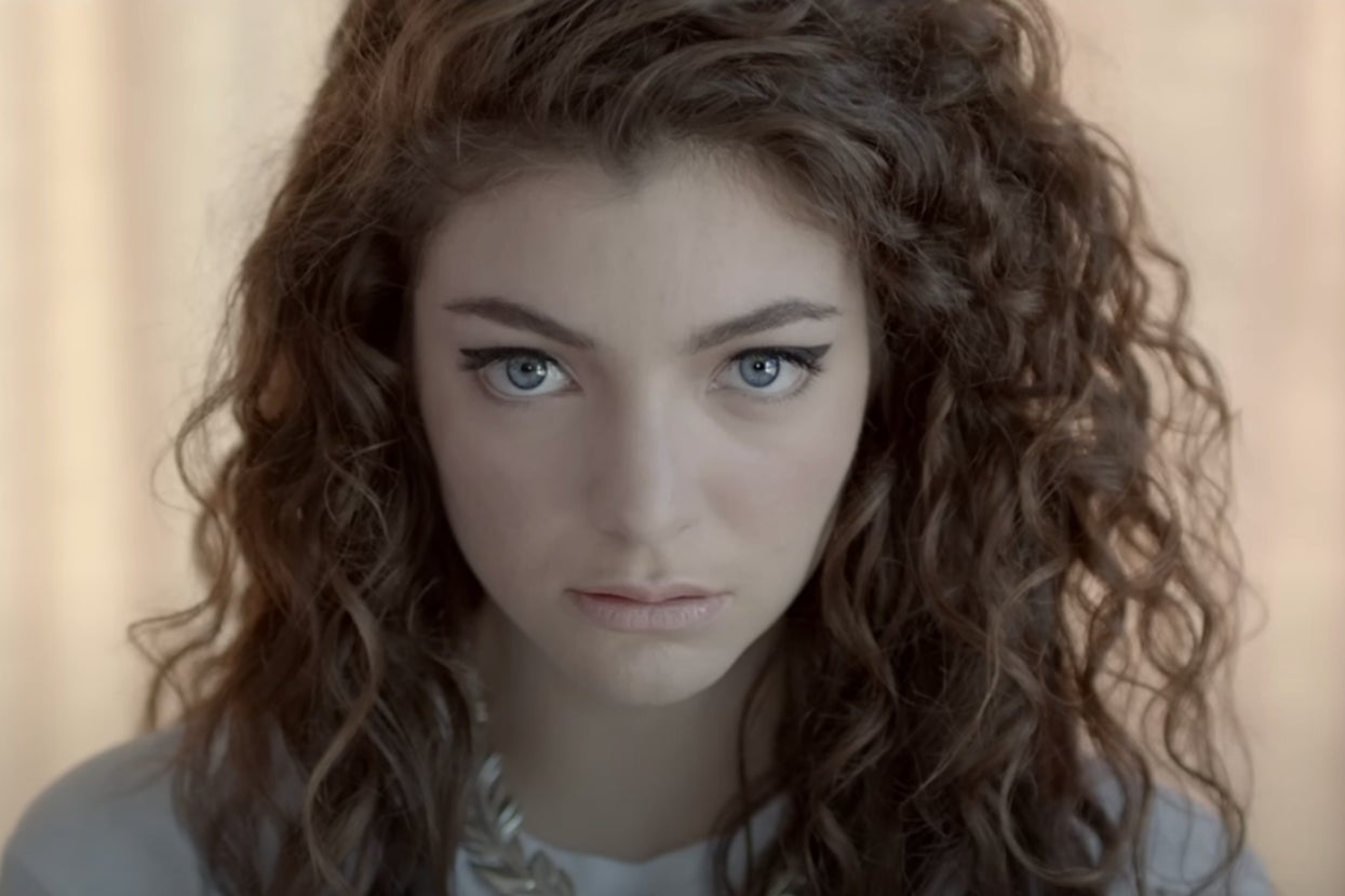 Lorde stares intently ahead, with her curly hair framing her face, in the Royals music video