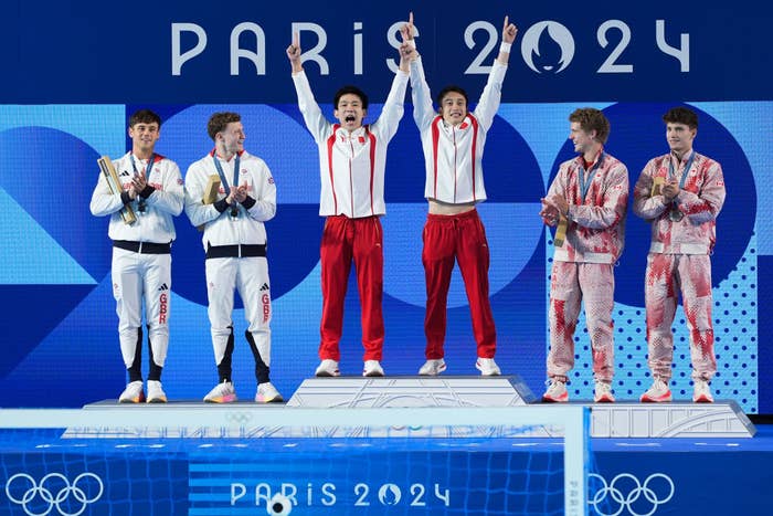 Gold medalists Lian Junjie and Yang Hao of Team China celebrate on the podium alongside silver medalists Thomas Daley and Noah Williams of Team GB and bronze medalists Rylan Wiens and Nathan Zsombor-Murray of Team Canada during the medal ceremony