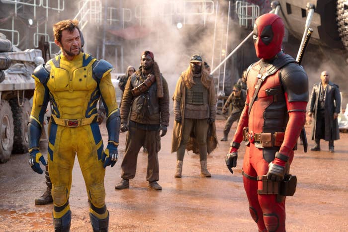 Hugh Jackman as Wolverine and Ryan Reynolds as Deadpool with various people behind them in a scene from &quot;Deadpool &amp;amp; Wolverine&quot;