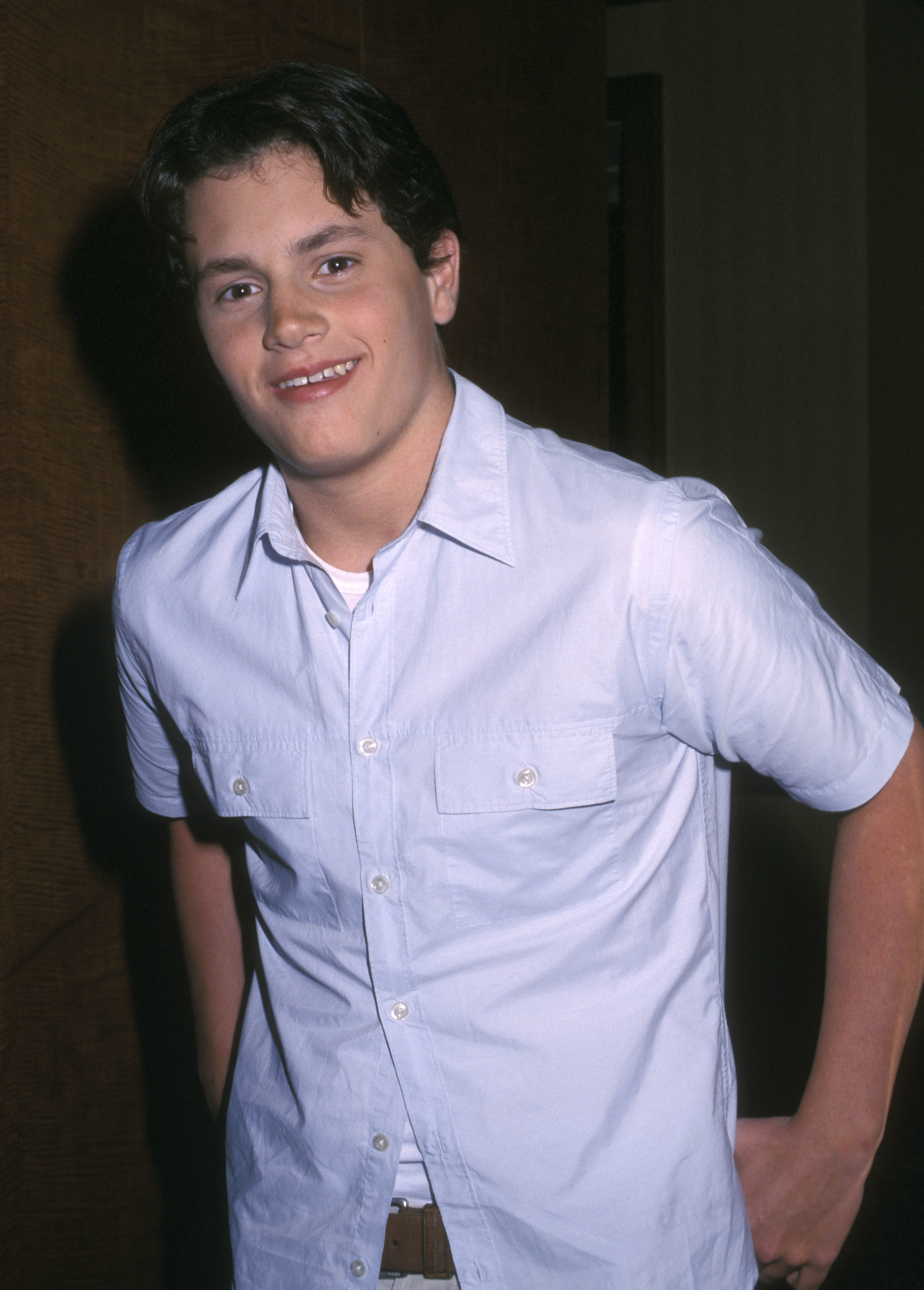 Young man standing and smiling, wearing a casual short-sleeved button-down shirt