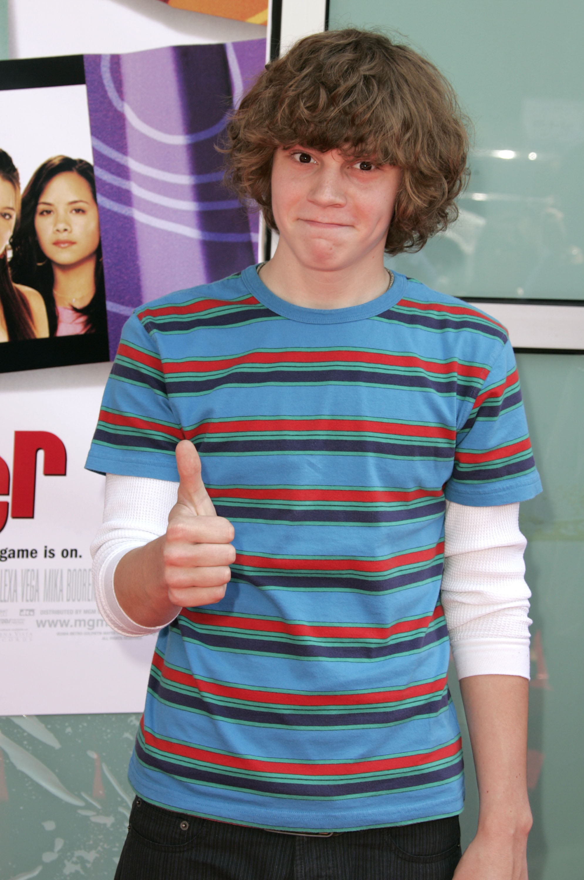 Evan Peters, in a striped shirt with long sleeves underneath, gives a thumbs up at a movie premiere