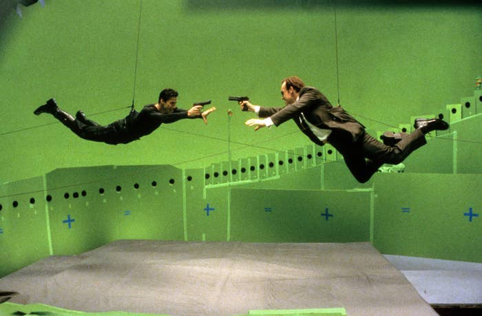 Keanu Reeves and Hugo Weaving filming an action scene while suspended by wires on the set of The Matrix