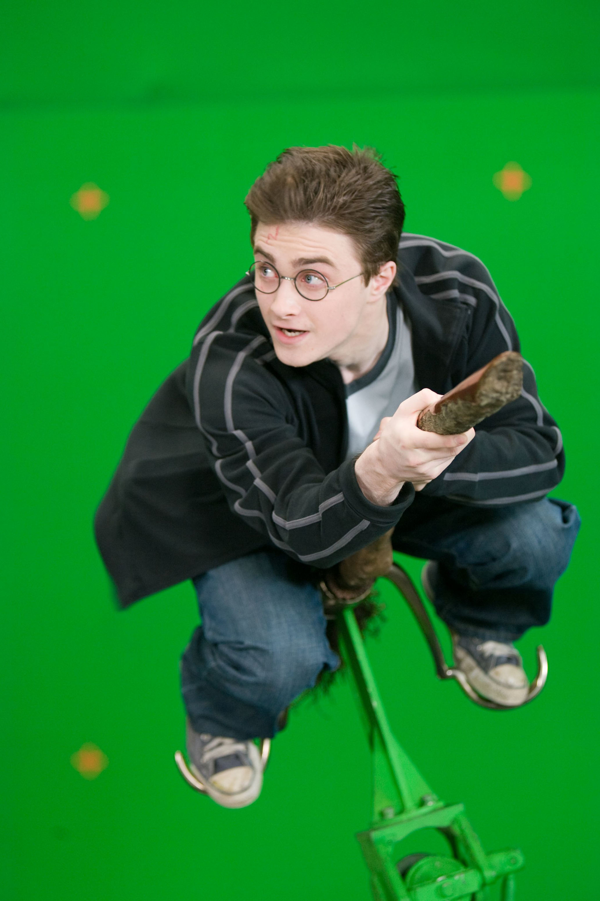 Daniel Radcliffe as Harry Potter on a broomstick, filming in front of a green screen for a movie scene